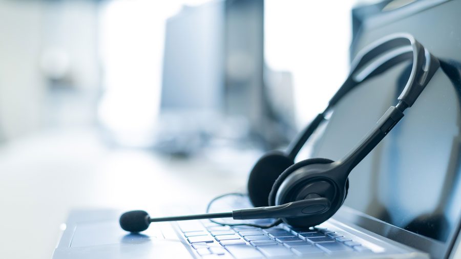 A headset used by a call centre on top of the keyboard of an open laptop